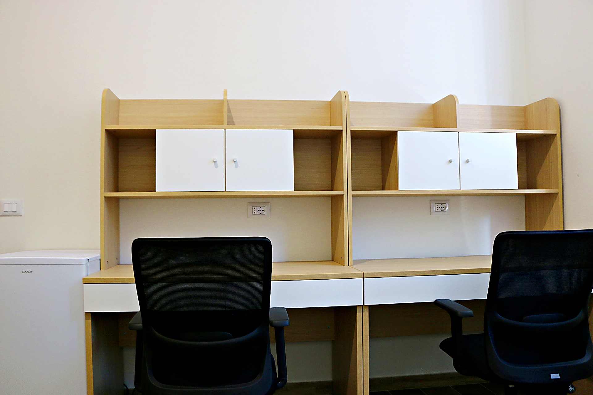 Side-by-side study desks with chairs in a double room