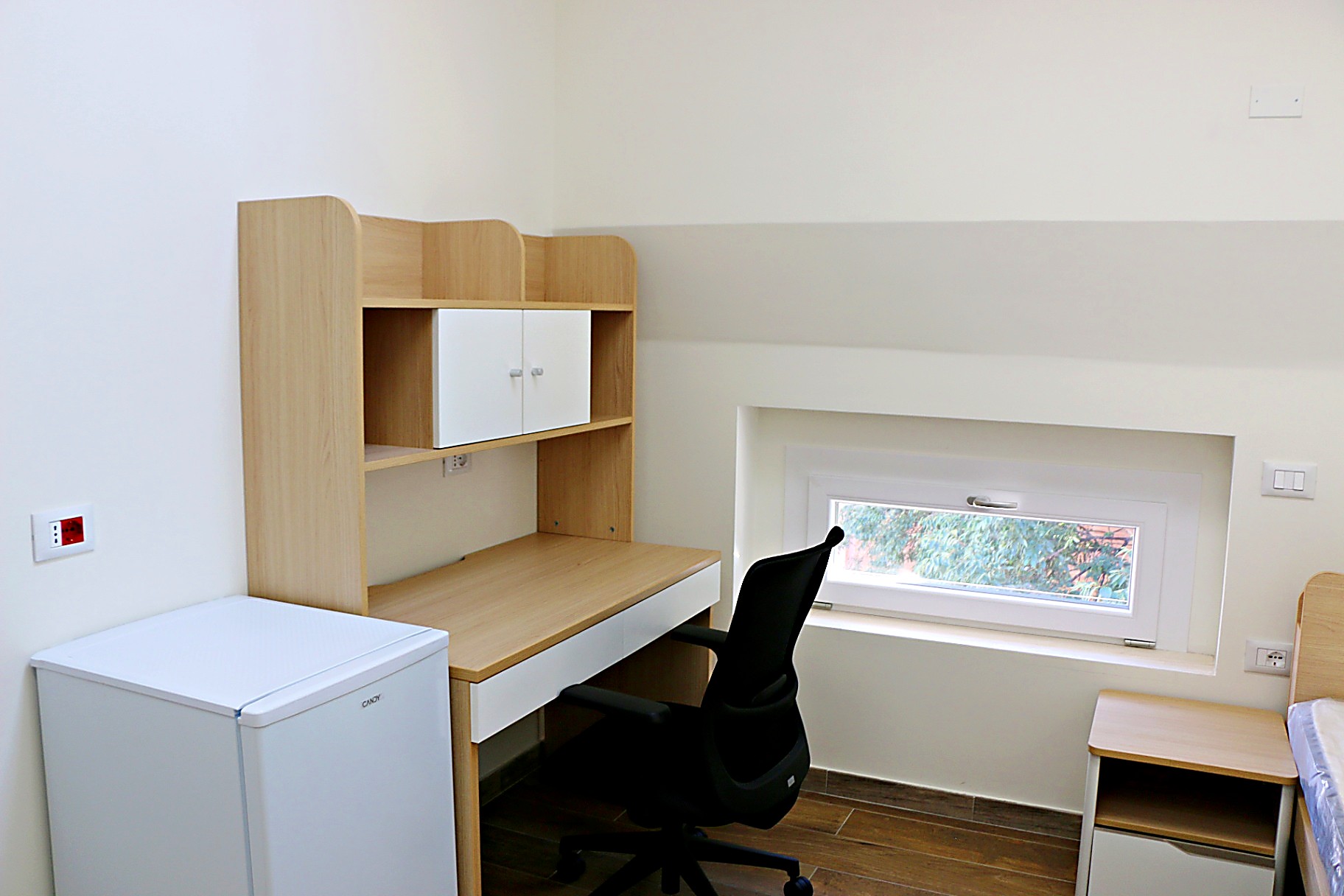 Study desk with shelving and mini-fridge in a single room